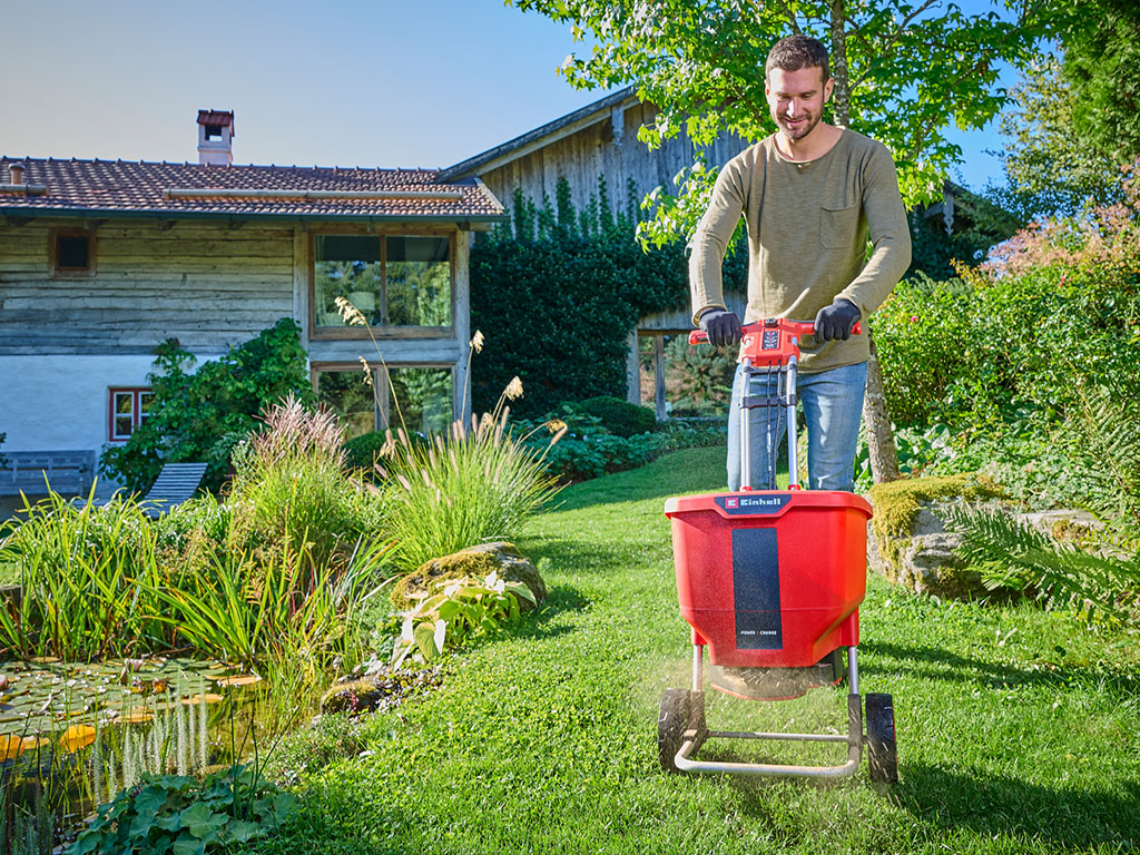 A man using the universal spreader in his garden. 