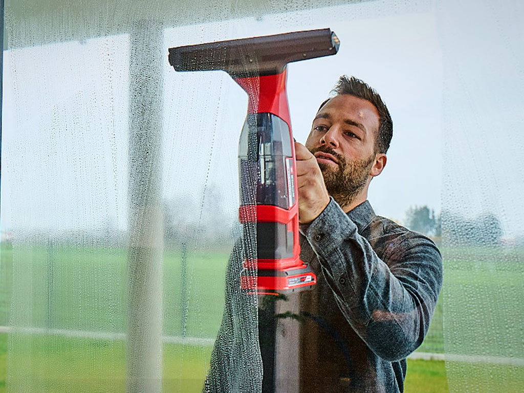 A man cleaning the window with the cordless window cleaner.