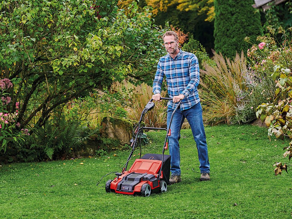 A man scarifying the lawn.