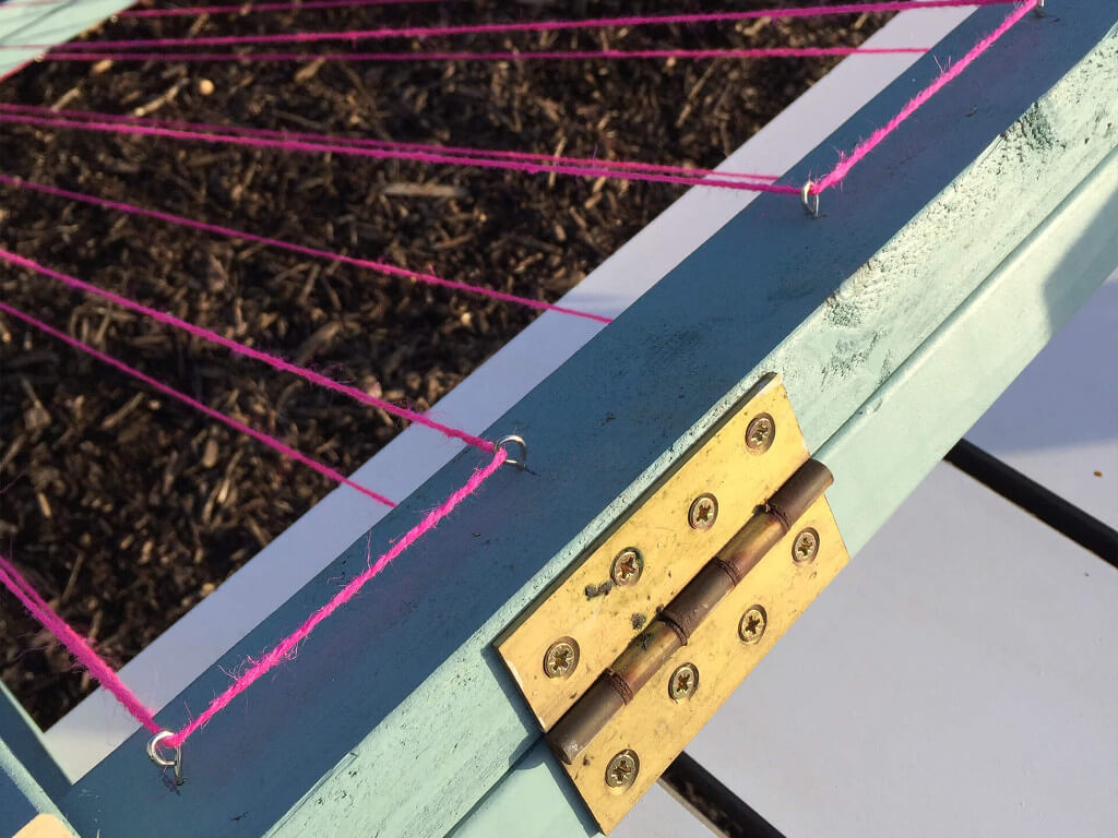Pink ropes that are attached on hooks of the wood piece. 
