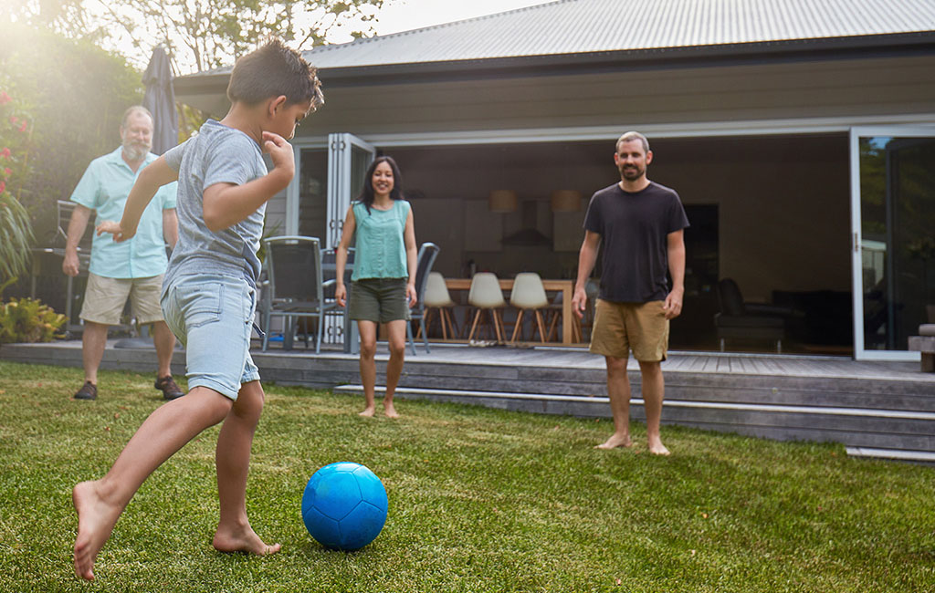 A little boy playing soccer with his family.