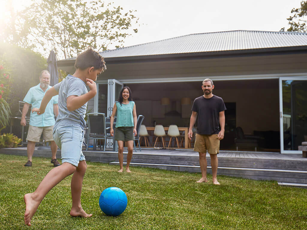 A little boy playing soccer with his family. 