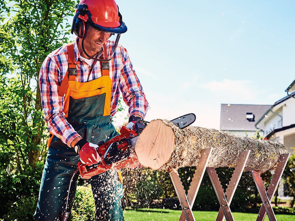 A man cutting up tree trunk with a chainsaw.