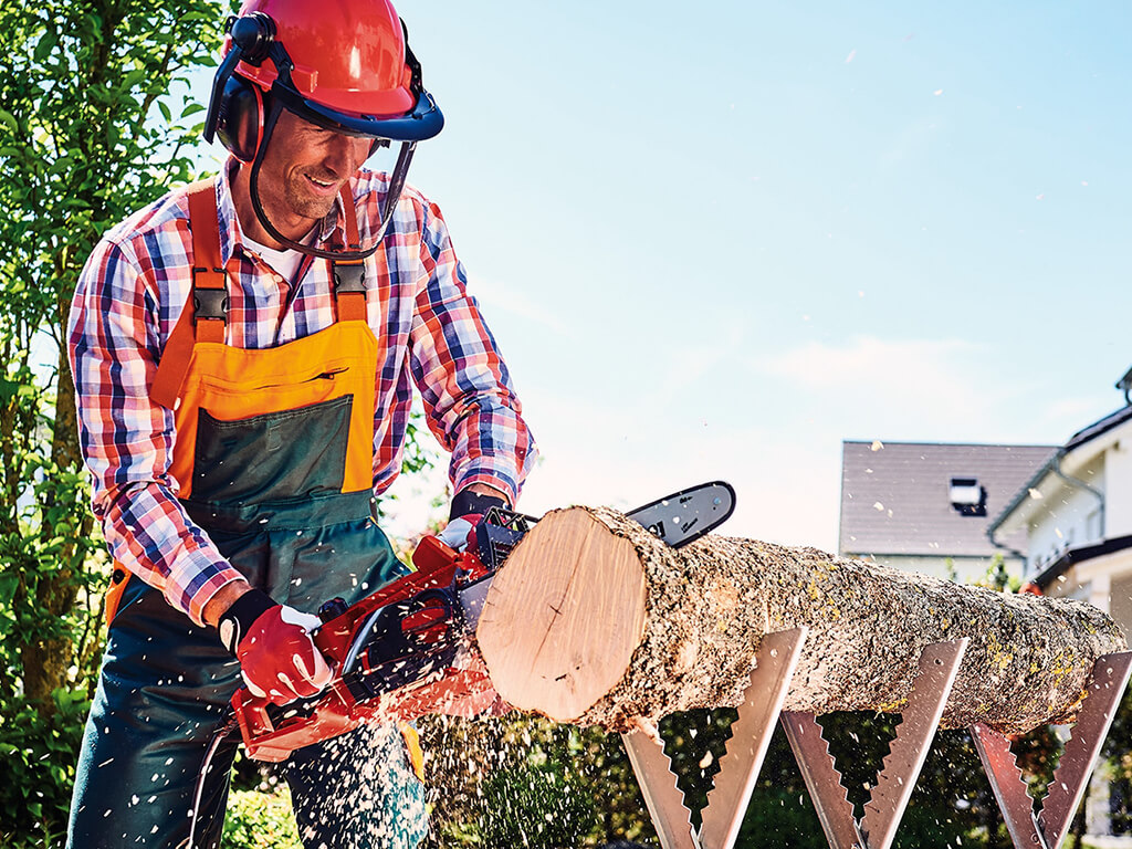 A man cutting up tree trunk with a chainsaw.