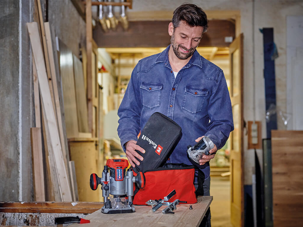 A man packs the accessories of the Einhell cordless router and edger set into the accompanying bag.