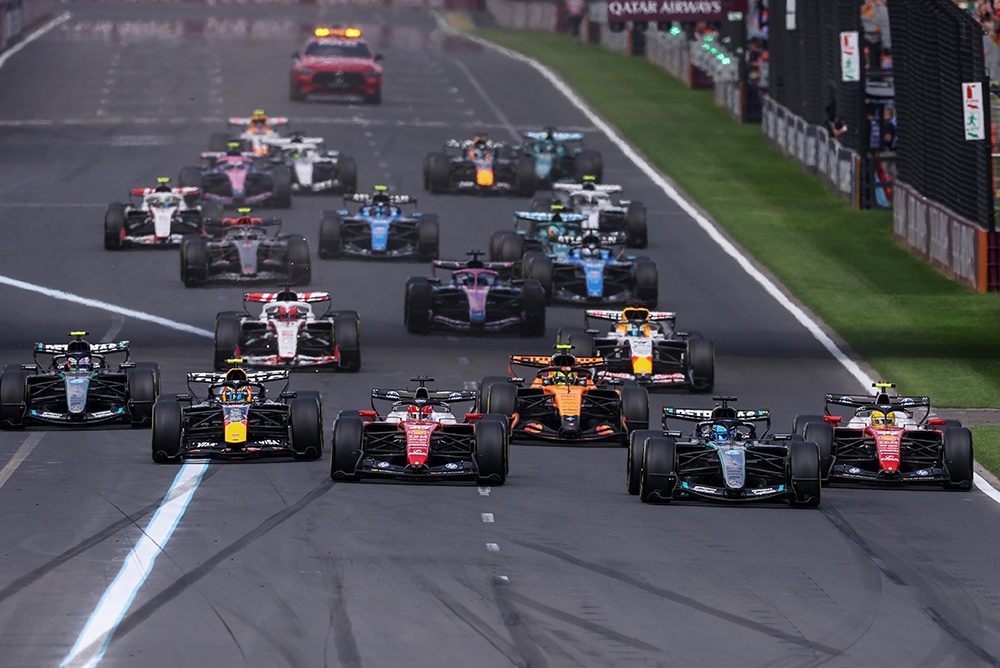 Multiple Formula 1 race cars at the start of a race on the track.