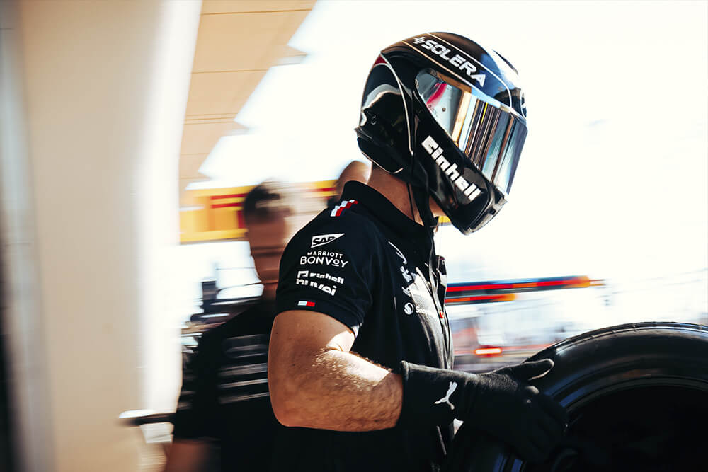 Image of a man carrying a tyre of a Formula 1 Mercedes car.