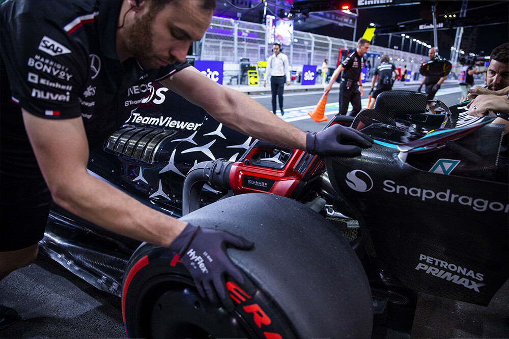 Formula 1 Mercedes race car getting pushed into the workshop by a mechanic.