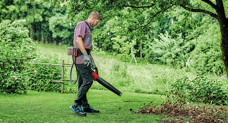 a man using the Einhell Battery Belt while working with a Einhell cordless Leaf Blower