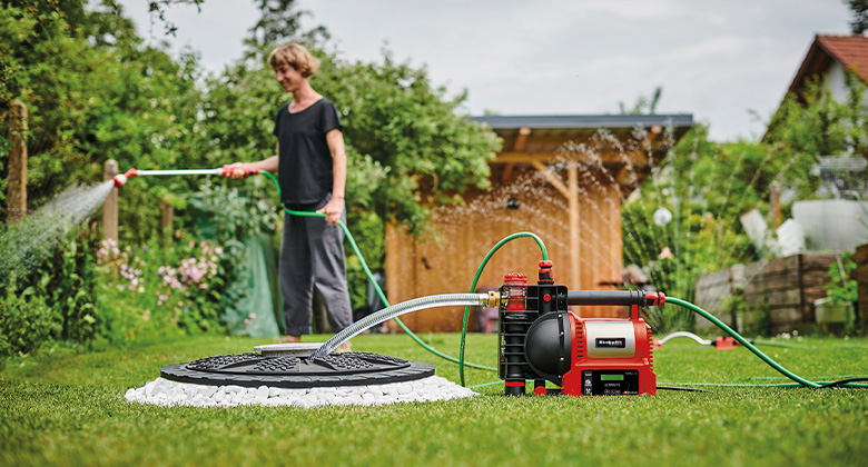 back: woman watering flowers in the garden; front: water pump pumps water