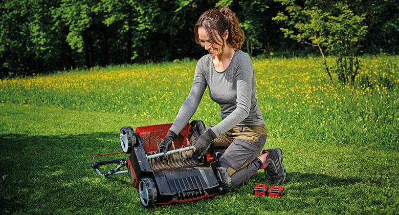 A woman is cleaning the blade reel of a scarifier
