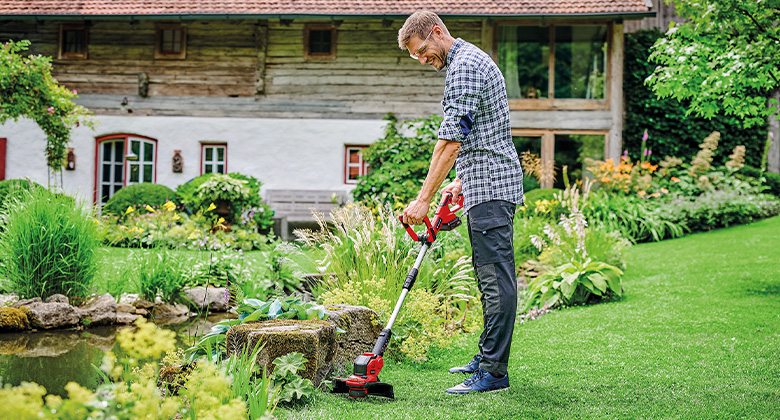 a man is working with a Einhell cordless trimmer