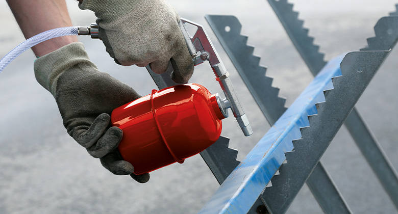 Close-up of an Einhell air compressor spray gun working on a metal surface.