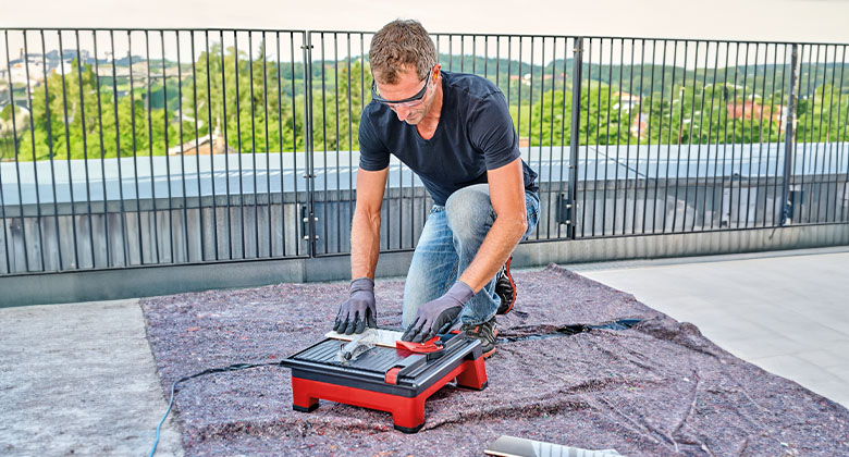A man using the Einhell cutting machine on a balcony.
