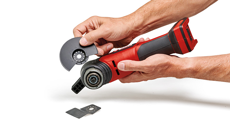 Hands hold a Einhell multi-tool and attach a blade to it, with another blade lying next to it.