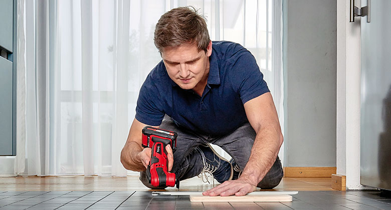 a man is working with a Einhell multifunctional tool in a kitchen