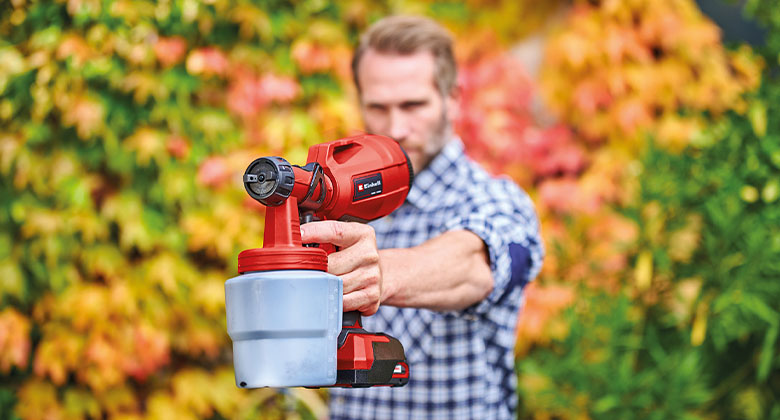 a man is holding an Einhell cordless paint sprayer