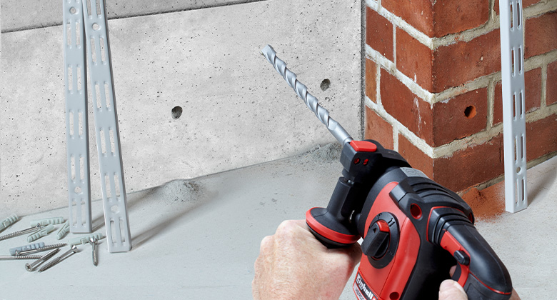 A Einhell rotary hammer is used to drill holes in a concrete wall and a brick wall.