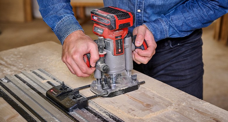An Einhell cordless router is used with a guide rail to mill precisely into wood.