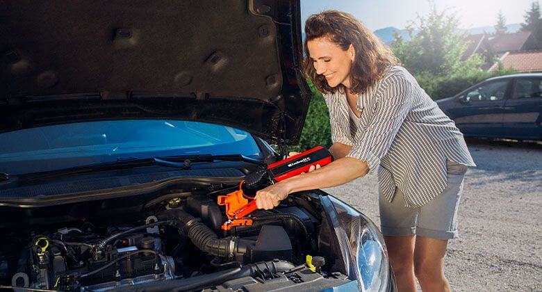 Woman starting car with a jump starter