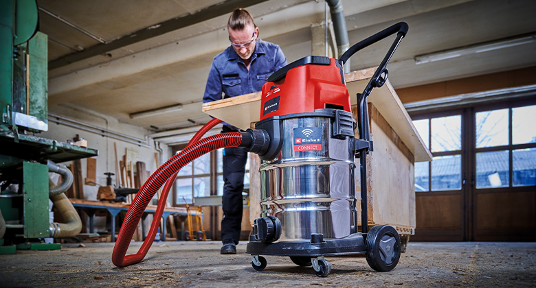 A man uses an Einhell cordless wet/dry vacuum in a workshop