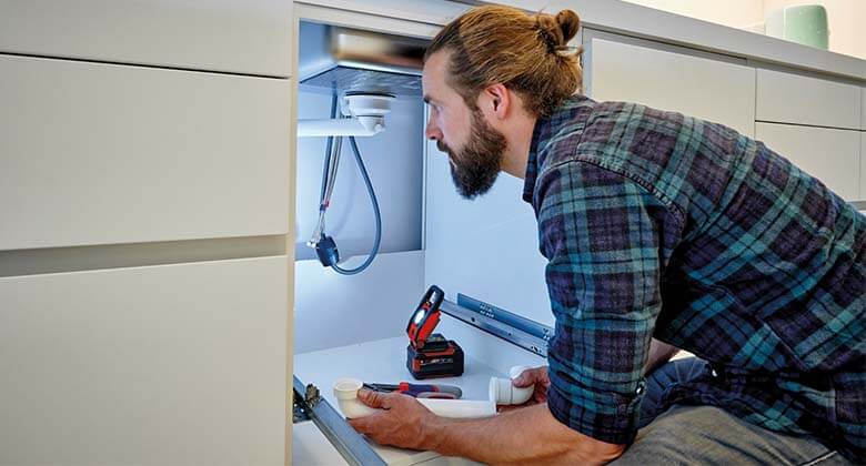 man working in a kitchen with a cordless light