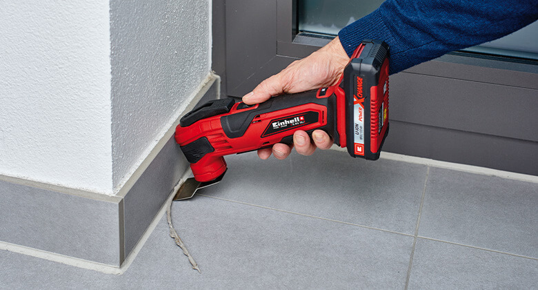 A cordless multifunction tool from Einhell scraping out a silicone joint.
