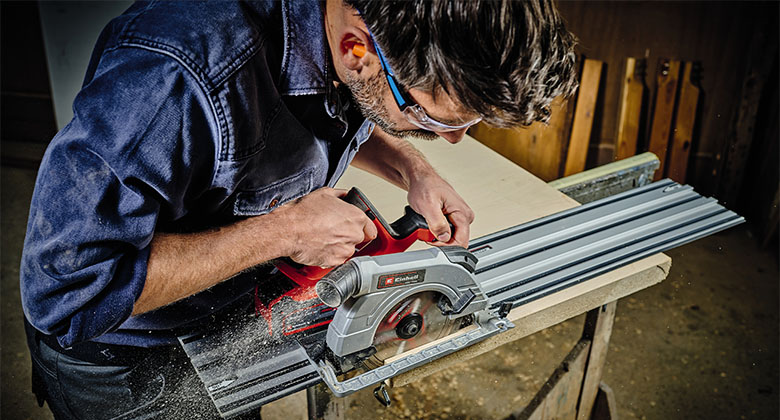 A man using a hand-held circular saw with a guide rail