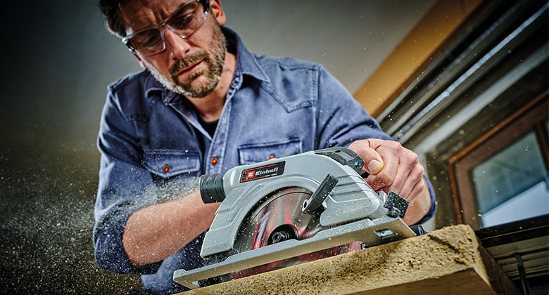 A man sawing wood with a cordless circular saw