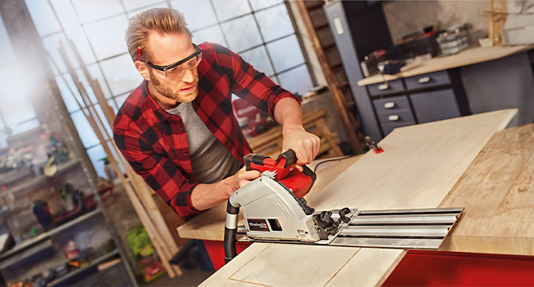man using a plunge cut saw in his workshop
