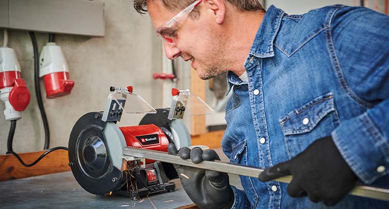man working with a bench grinder