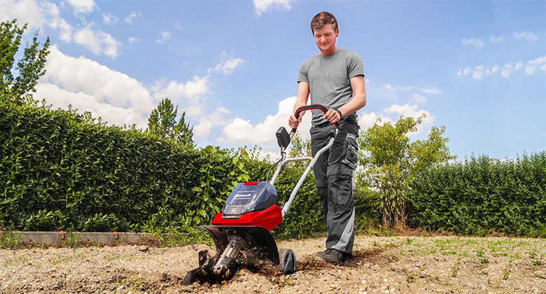 man working with tiller in the garden to loosen the ground
