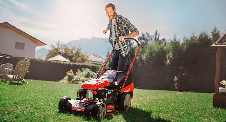 A man starting his petrol lawnmower.
