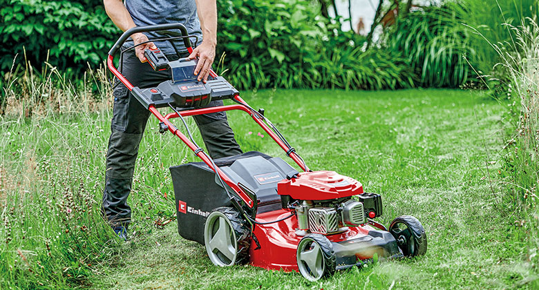 A man putting a battery for the electric start function into a petrol lawnmower.