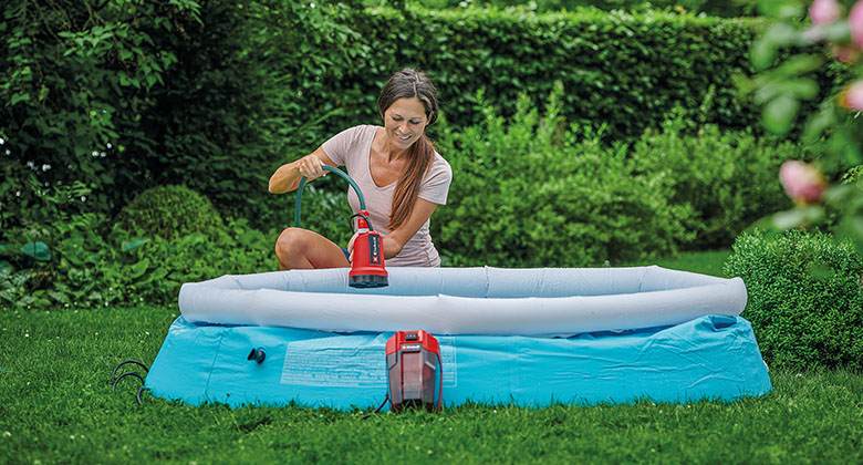 A woman placing a clear water pump into a small pool. 